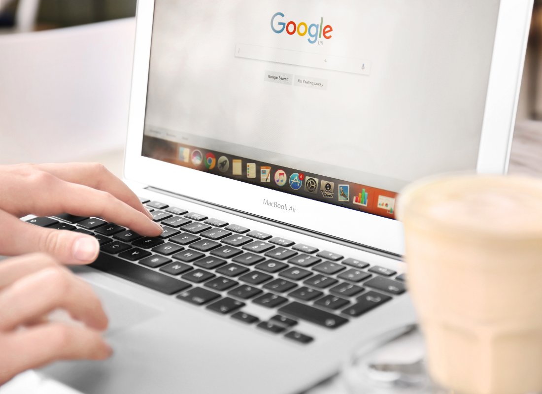 Mains d'une personne qui effectue une recherche sur Google avec un ordinateur portable