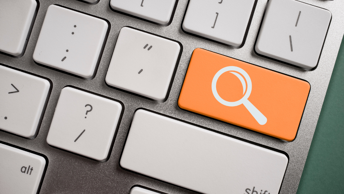 Clavier d'ordinateur avec un bouton orange où se trouve une loupe blanche