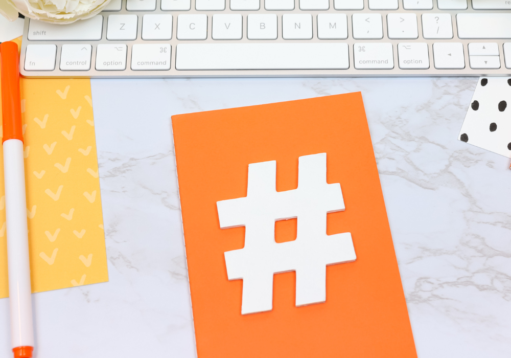 white hashtag on orange background, orange pen and white keyboard