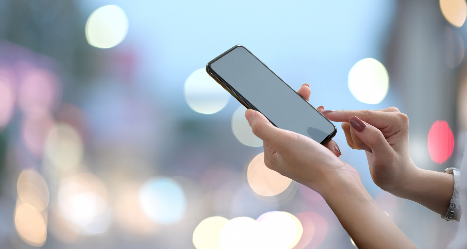 mains de femme tenant un cellulaire avec fond de lumières