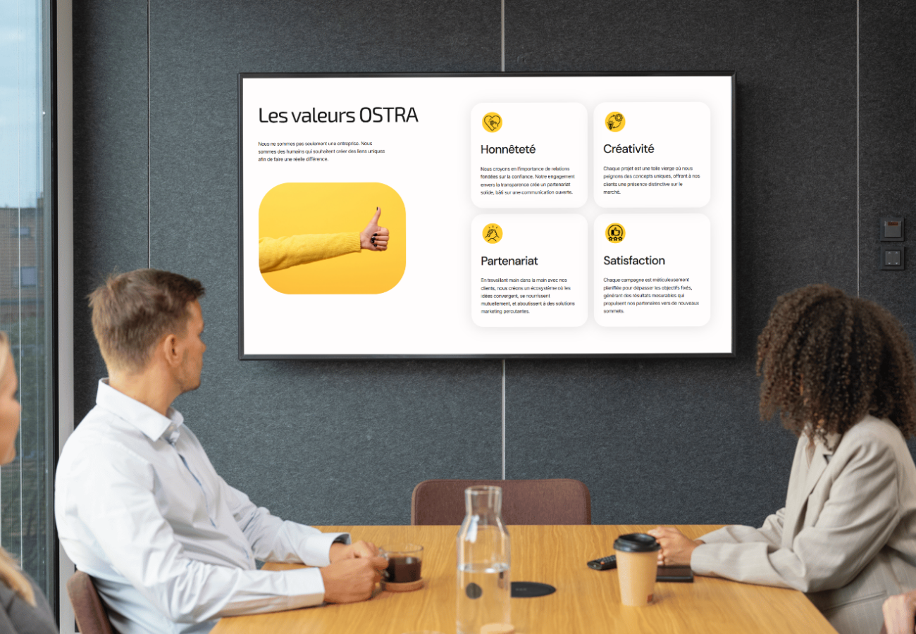 Mockup du site de Ostra Marketing en écran d eprésentation dans un bureau avec des gens