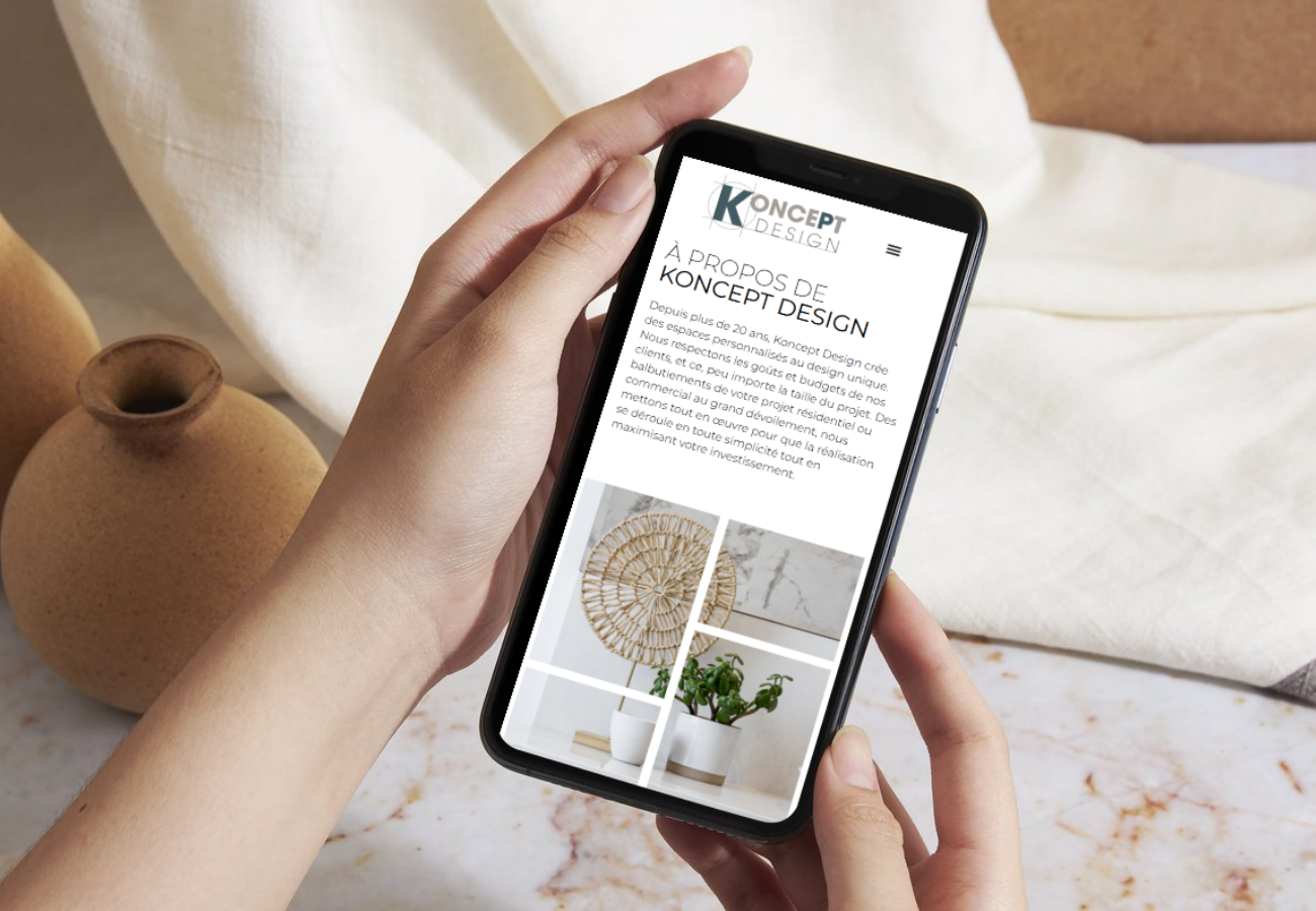 Site web de Koncept Design dans un cellulaire tenu par deux mains de femme